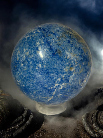 Vibrant blue Azurite clusters and polished stones glowing under candlelight on a ritual altar at Raven’s Cauldron.