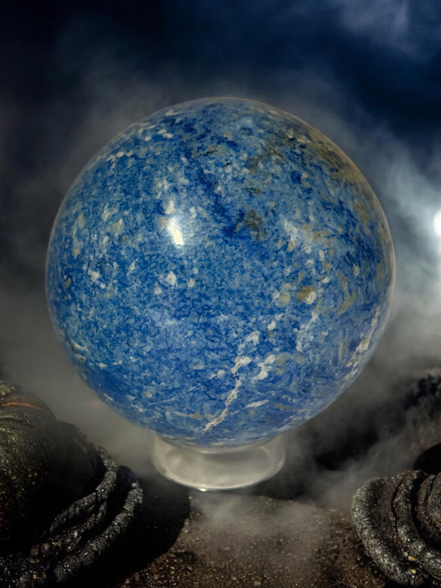 Vibrant blue Azurite clusters and polished stones glowing under candlelight on a ritual altar at Raven’s Cauldron.