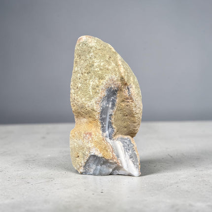 Grey and white agate cut base with natural quartz inclusions weighing 522 grams standing upright on a polished flat base from Raven's Cauldron.