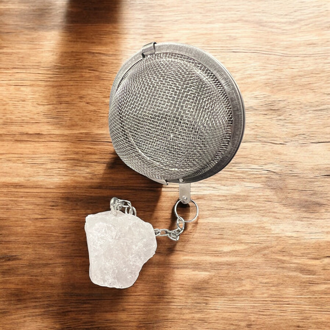 Metallic tea ball infuser with a chain on a wooden surface, Raven's Cauldron, 6 N Sandusky St, Delaware, OH 43015