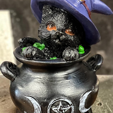 Nemesis Now Hubble black cat sitting inside a witch's cauldron wearing a purple witch's hat resin figurine.