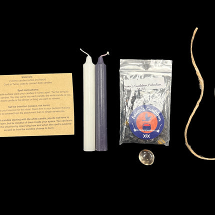 Raven's Cauldron Cord Cutting Ritual Kit with black and white candles, twine, Smoky Quartz tumble, Protection Blend Chips, and ritual guide