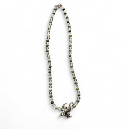 Necklace with green beads and a silver dragon pendant on a white background