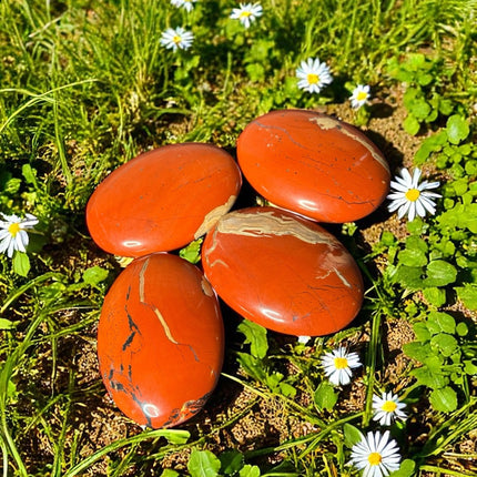 Shop Red Jasper Palm Stones at Raven’s Cauldron. Each 80g stone, ~2.75 inches long, is mined in Brazil and polished to showcase beautiful reds and whites. Perfect for grounding and healing.