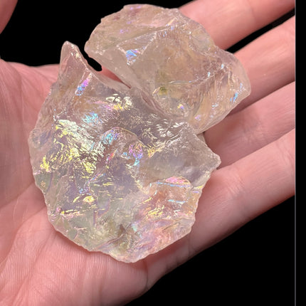 Iridescent crystal held in a hand against a black background