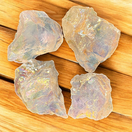 Four iridescent crystal stones on a wooden surface
