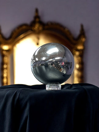 Silver metallic sphere on a black surface with a reflective gold mirror in the background, terahertz sphere, Ravens Cauldron, 6 N Sandusky St, Delaware, OH 43015