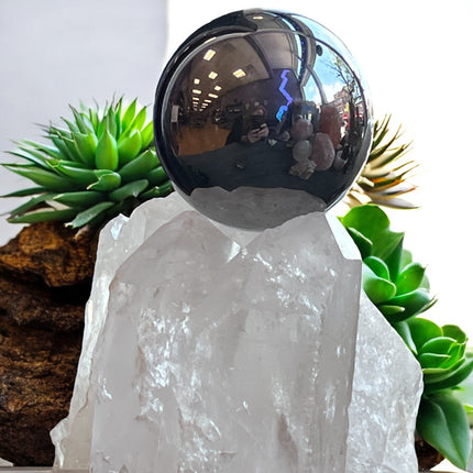 Metallic sphere on a crystal base with plants in the background, terahertz sphere ,Ravens Cauldron, 6 N Sandusky St, Delaware, OH 43015